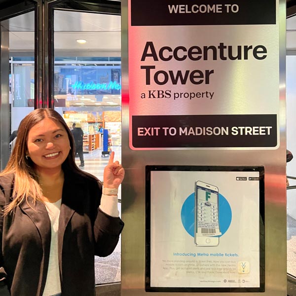 Daniella Soriano Success Story Daniella Soriano pointing to an Accenture Tower sign