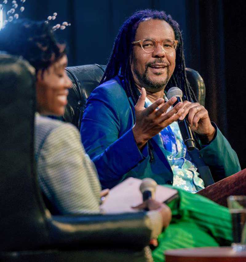 Whitehead, a dark skin Black man with glasses and locs, speaks to a moderator on stage during the St. Louis Literary Award reception.